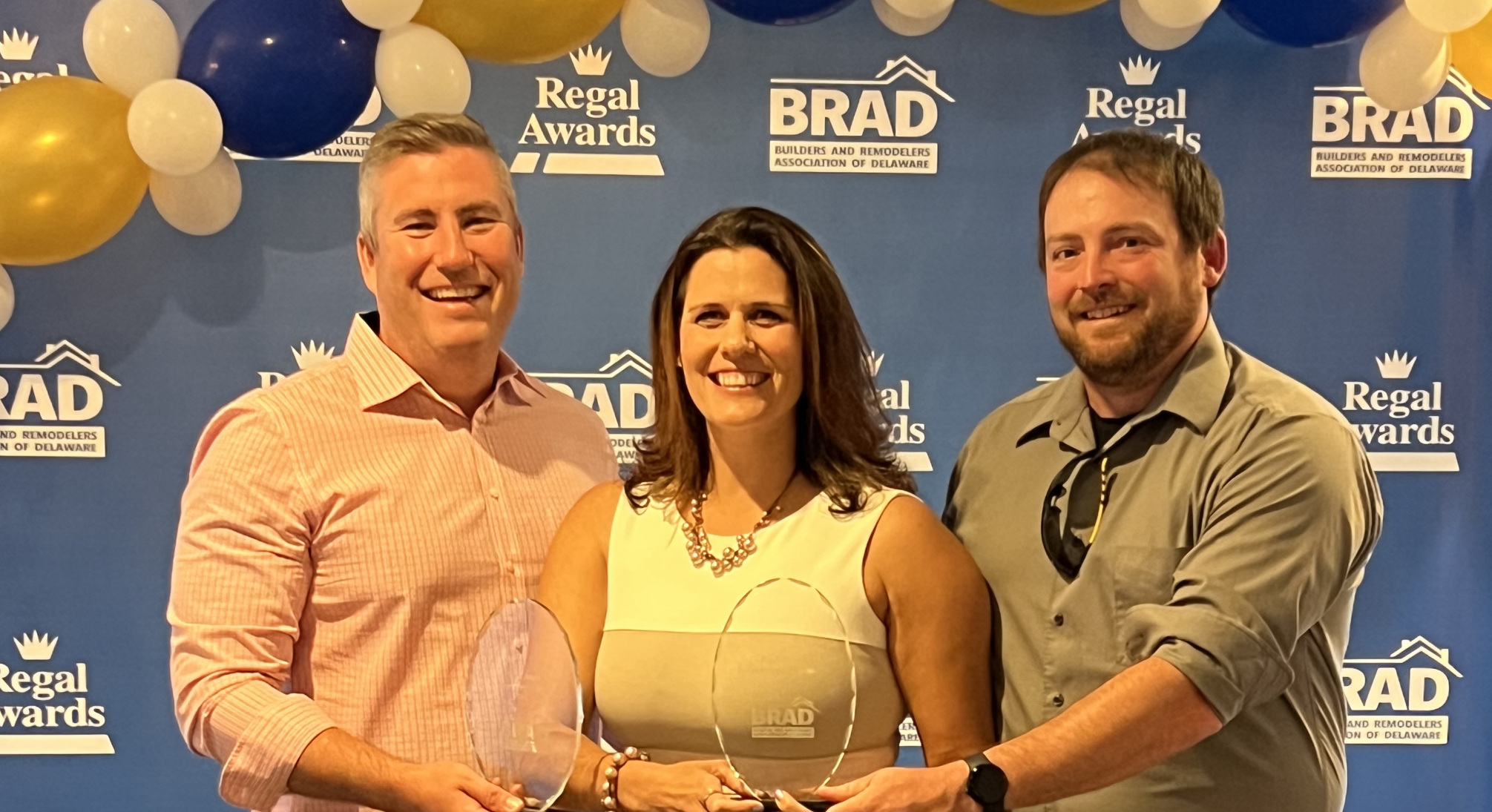 Adrian and Julleanna Seely, owners of Seely Homes in Bridgeville, and Nathaniel Maynard (right), site superintendent, accept two Regal Awards for Custom Homes from BRAD.