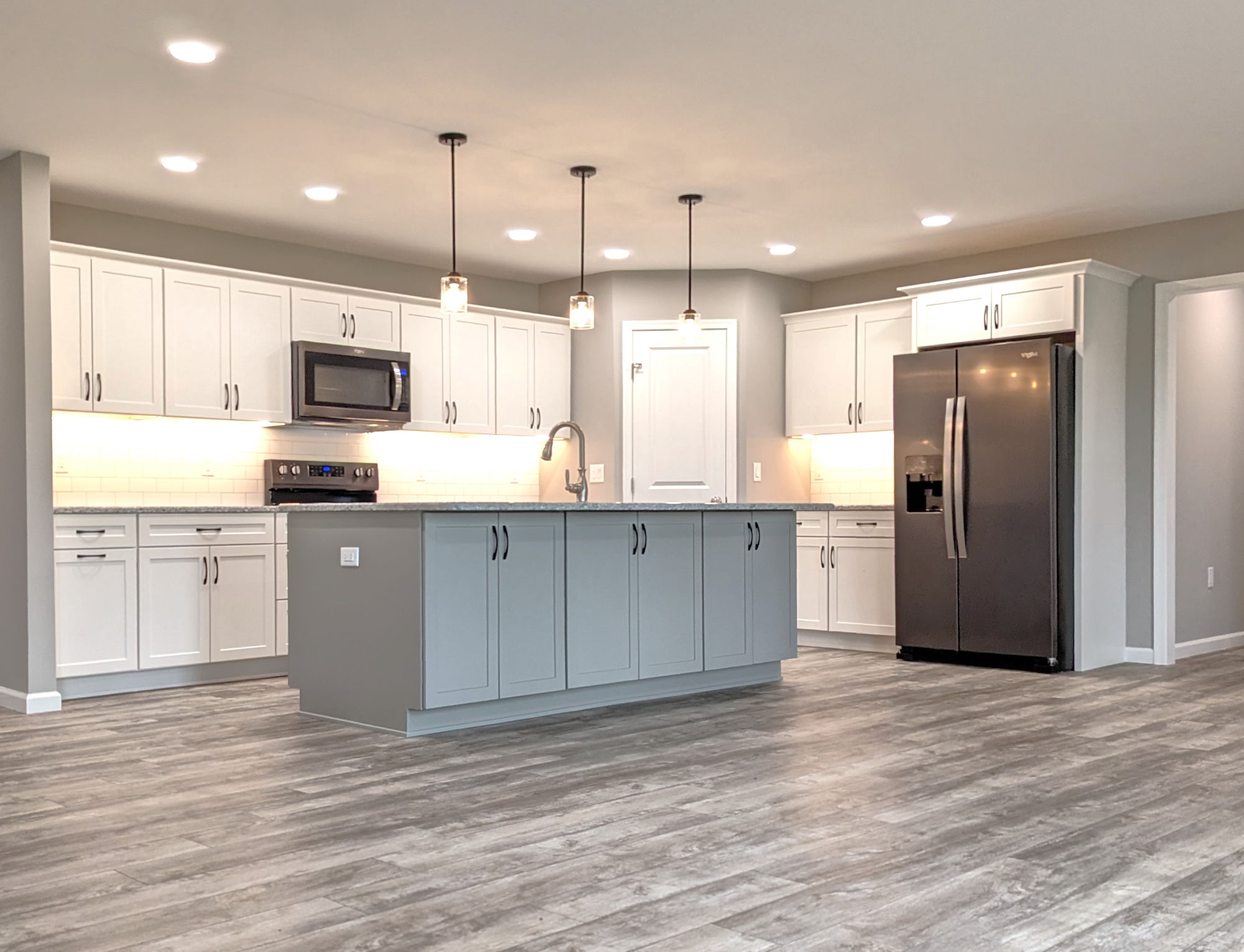 Seely Homes Neal Kitchen Mantra Omni Snow Mineral Gray Island Cabinets Doors Black Stainless Appliances Corner Pantry Winslow Pendants Under Cabinet Lighting Timberline Roclock LVP Floor